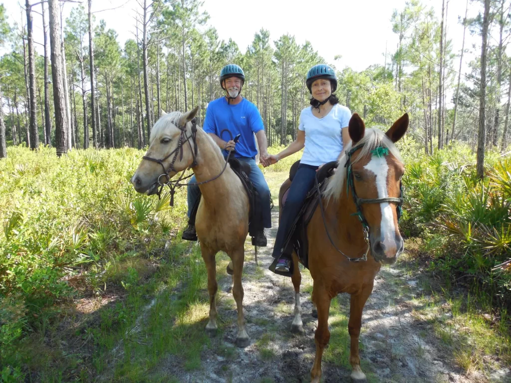 couple holding hands while riding Tennessee Walking Horses down a trail 